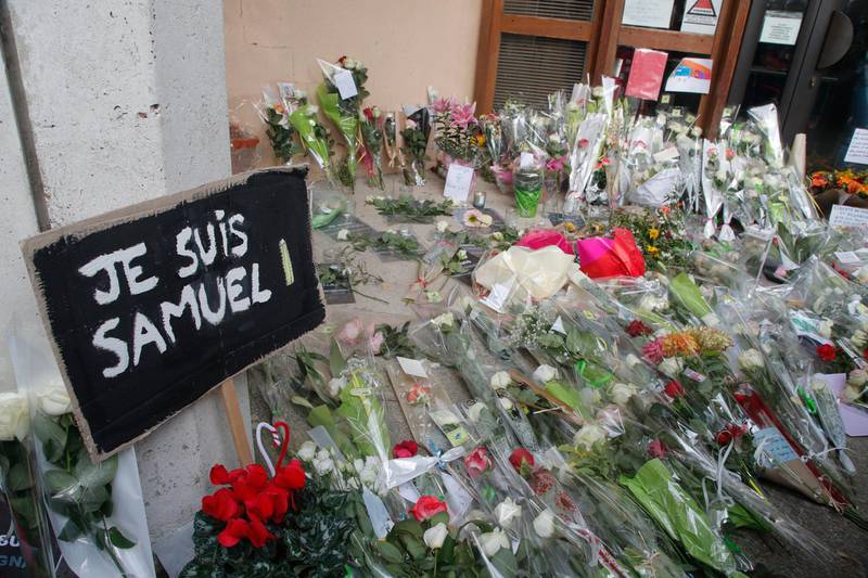 FILE - In this Oct.17, 2020 file photo, a poster reading "I am Samuel" and flowers lay outside the school where slain history teacher Samuel Paty was working, in Conflans-Sainte-Honorine, northwest of Paris. French lawmakers tackle a bill on Monday to dig up radical Islam by its roots in the country, beliefs that authorities maintain are creeping into public services, associations, some schools and online with the goal of undermining national values. (AP Photo/Michel Euler, File)