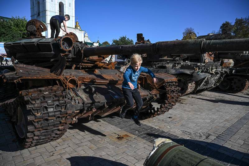 A boy playing on a destroyed Russian tank on display in Kyiv. AFP