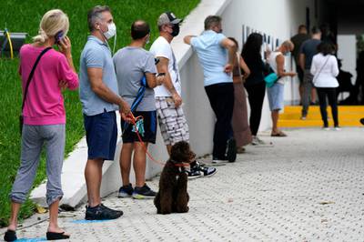 William Heuseler, second from left, waits in line to vote with his dog Ziggy, outside of an early voting site, Tuesday, October 20. AP