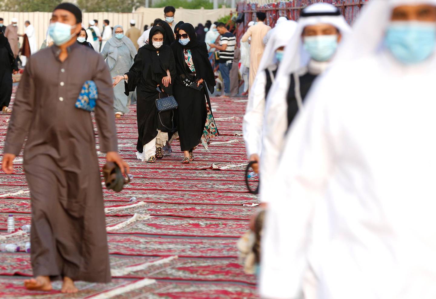 Muslim women, center rear, wearing masks to curb the spread of coronavirus outbreak, walk on carpets after they performed Eid al-Fitr prayer marking the end of the holy fasting month of Ramadan at al-Mirabi Mosque in Jiddah, Saudi Arabia, Thursday, May 13, 2021. (AP Photo/Amr Nabil)