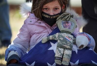 Brielle Robinson, whose father died from a burn pit-related illness, holds a doll with her father's photograph during a news conference on the need to pass the Pact Act before its passing in 2022. Reuters
