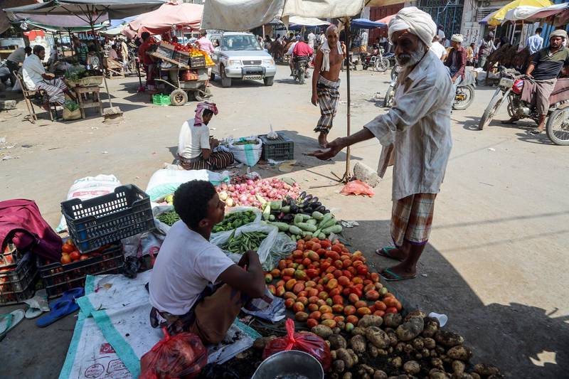 A Yemeni buys produce from a vegetable peddlar at a market in the Huthi-held Red Sea port city of Hodeida on December 14, 2018.  / AFP / ABDO HYDER
