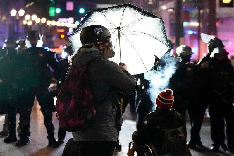 A person holds up an umbrella in front of a line of police officers during protests in Portland, Oregon. AP Photo