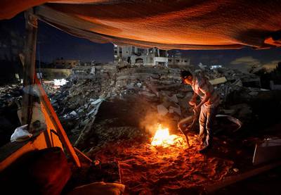 A Palestinian man lights a fire amid the rubble of his house in the Gaza Strip, which was destroyed by an Israeli air attack. Reuters