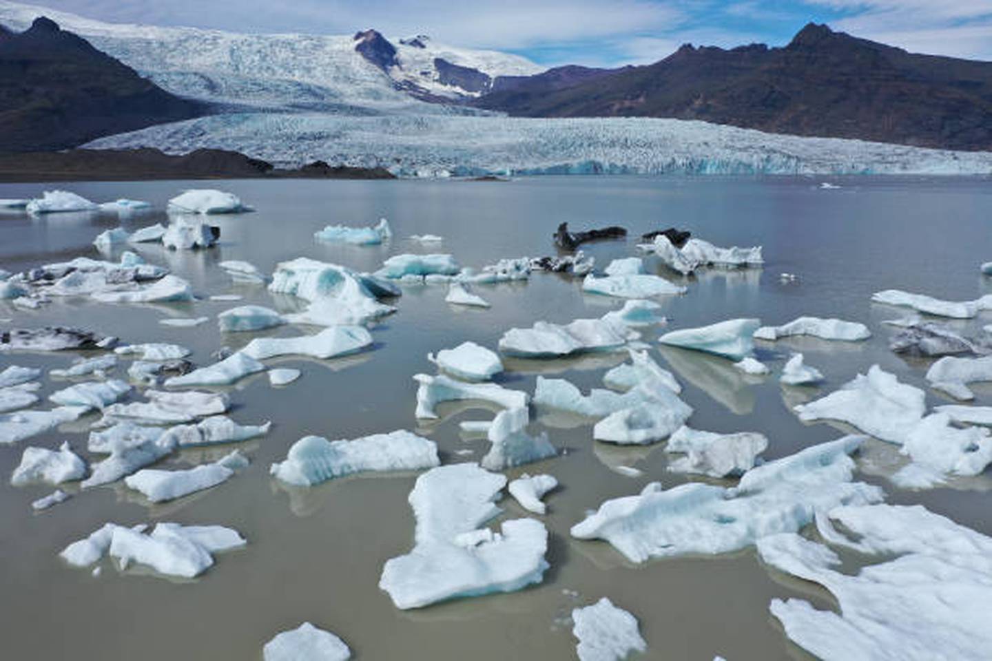 Chunks of ice from the Fjallsjokull glacier, seen behind, in a process called calving float, on Fjallsarlon lake, August 14, 2021 near Hof, Iceland. Getty