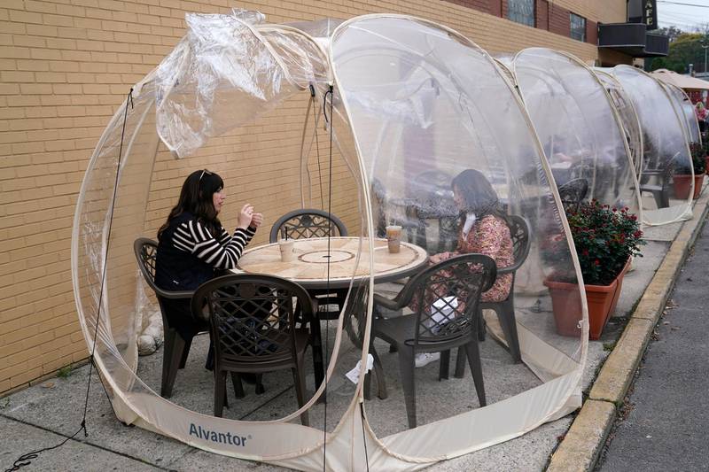Aviva Markowitz, left, and Rivka Alter enjoy a drink in a protective bubble at the Lazy Bean Cafe in Teaneck, New Jersey. AP Photo