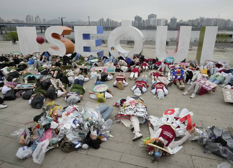 Environmental activists, some wearing outfits made from plastic waste, lie down on the ground during a campaign against climate change in Seoul, South Korea. AP Photo