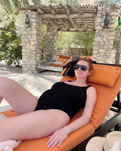 Lindsay Lohan displays her growing bump as she relaxes by the pool in Oman