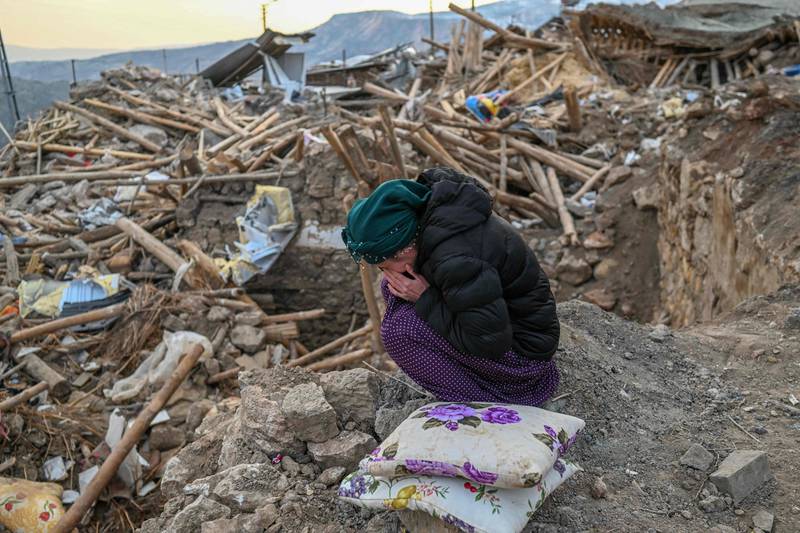 A woman cries as she sits atop the rubble of her collapsed house in Yaylakonak village in Adiyaman, in Turkey. AFP