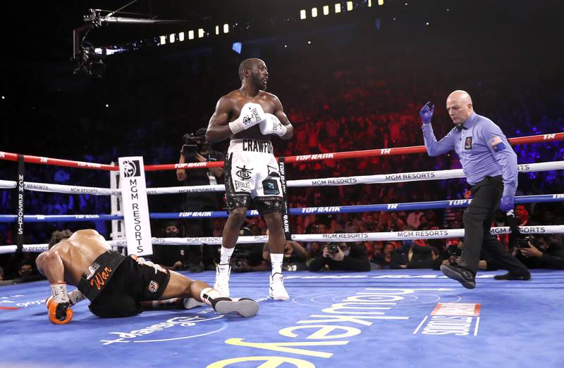 Referee Celestino Ruiz moves in to protect Shawn Porter after Porter was knocked down in the 10th round by WBO champion Terence Crawford. AFP
