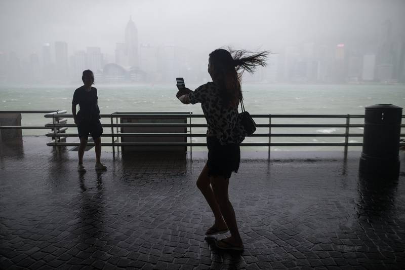 People take photos on the Victoria Harbour waterfront in Hong Kong. Tropical storm Pakhar is expected to skirt within 150 km southwest of Hong Kong by midday as the region is still reeling from the effects of Typhoon Hato.  Jerome Favre / EPA