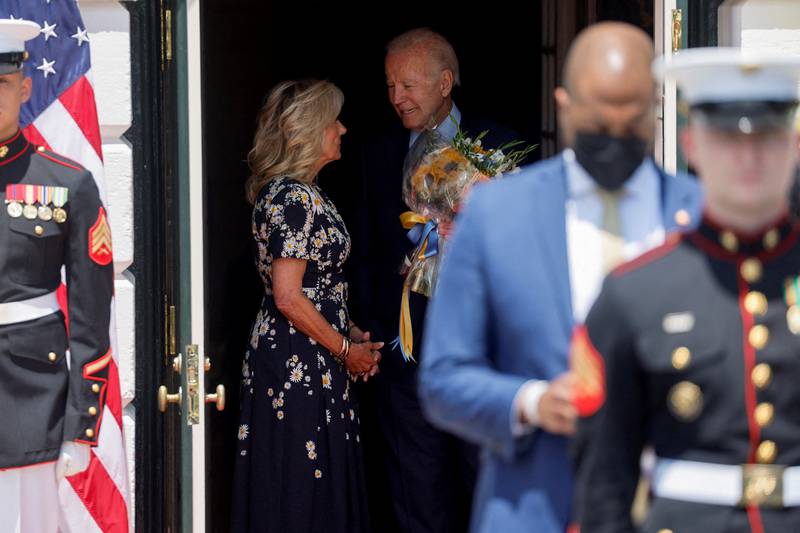 Mr Biden holds flowers while standing next to his wife at the White House. Reuters