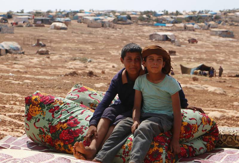 Displaced Syrian boys who fled from regime raids sit in a camp in Kafr Lusin. AFP