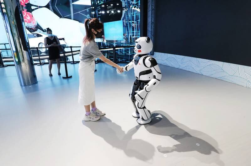 A woman shakes hands with the panda robot. Photo: EPA