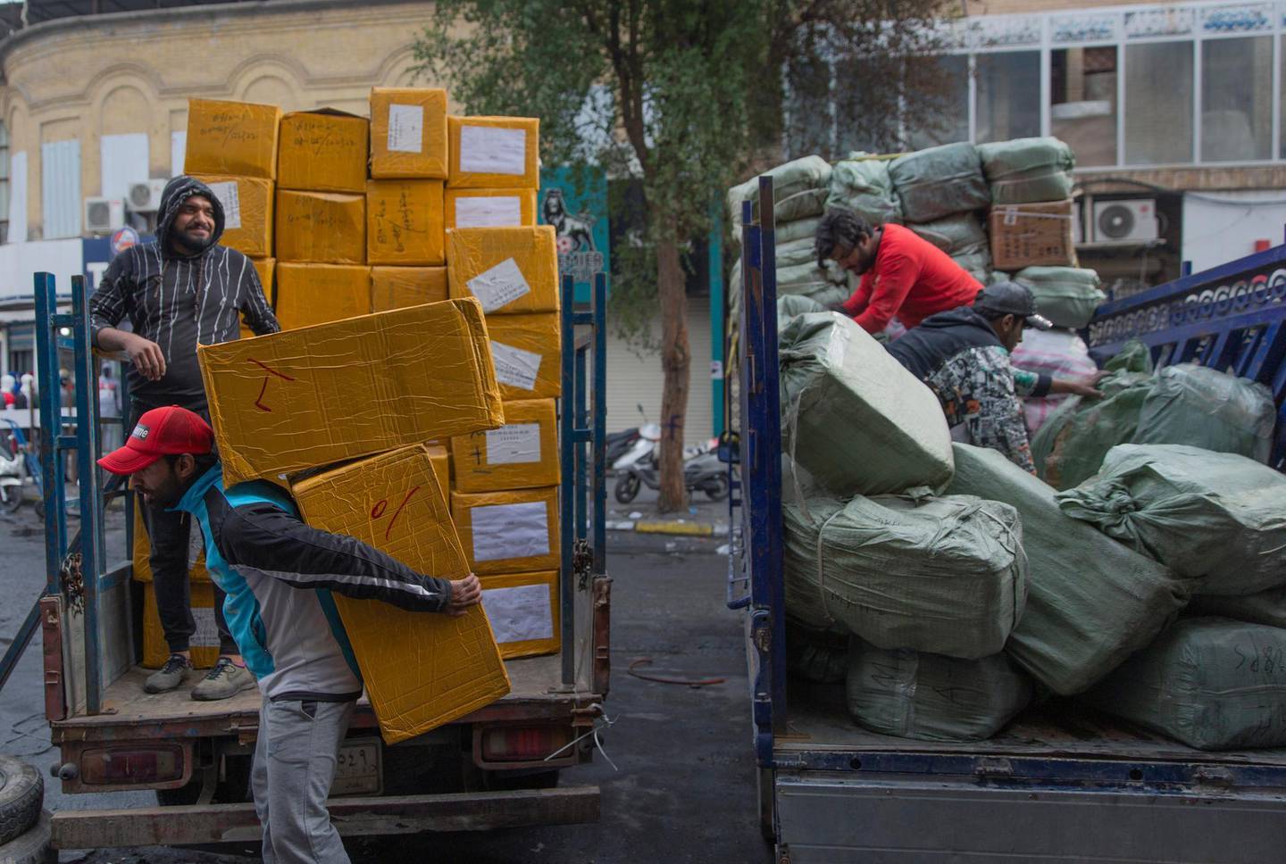 In this Monday, Dec. 16, 2019 photo, labors load salvaged products from a sports supplies store onto trucks, after the whole building caught fire during clashes between protesters and riot police last Sunday, at the commercial and historic al-Rasheed street, in the center of Baghdad, Iraq.  With Iraq's leaderless uprising now in its third month, the protracted street hostilities, internet outages, blocked roads and a general atmosphere of unease are posing risks to Iraq's economy. (AP Photo/Nasser Nasser)
