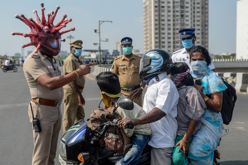 Police inspector Rajesh Babu wearing coronavirus-themed helmet speaks to a family on a motorbike at a checkpoint during a government-imposed nationwide lockdown in Chennai. AFP