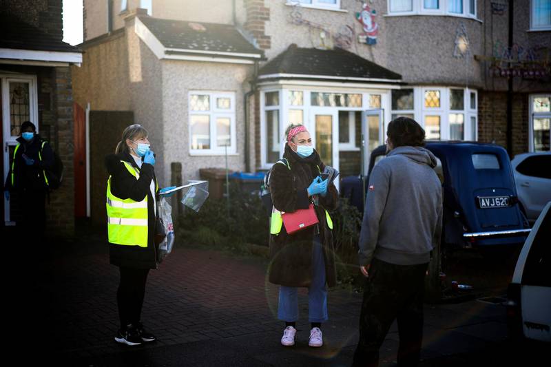 Workers talk with a resident as they deliver home test kits in Pollards Hill, London. Reuters