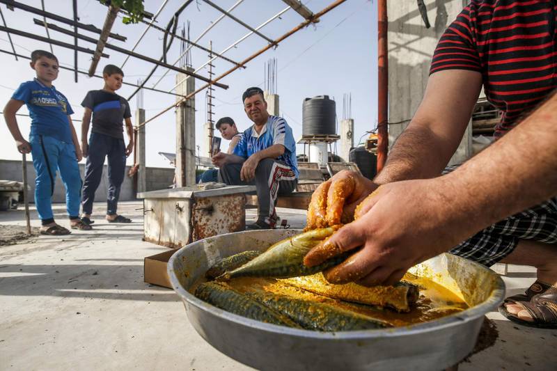 Palestinian family members prepare to smoke mackerel on the roof of their house in preparation for the upcoming Eid al-Fitr holiday which marks the end of the Islamic holy month of Ramadan, in the southern Gaza Strip city of Rafah.   AFP