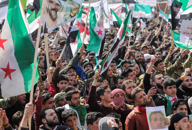 People carry banners and opposition flags during a demonstration, marking the 10th anniversary of the start of the Syrian conflict, in the opposition-held Idlib, Syria March 15, 2021. REUTERS/Khalil Ashawi