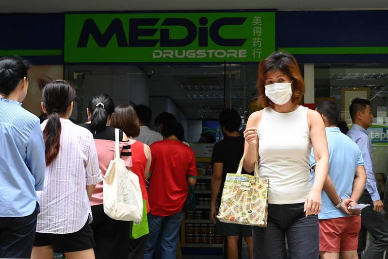 People queue outside a pharmacy to purchase protective face mask, thermometer and hand sanitizer in Singapore.  AFP