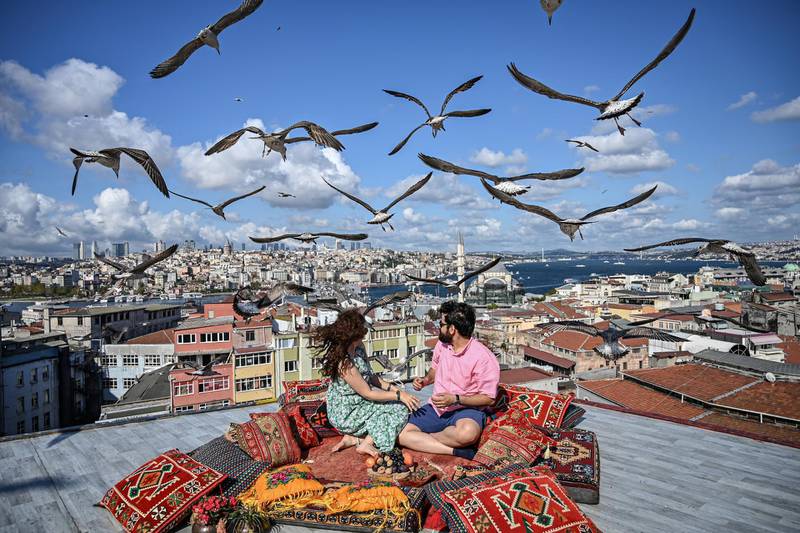 A couple sit on the terrace of a cafe in Istanbul as seagulls fly over them on September 10, 2019. (Photo by Ozan KOSE / AFP)