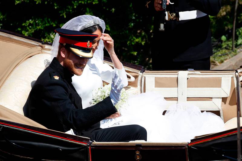 Britain's Prince Harry, Duke of Sussex (L) and his wife Meghan, Duchess of Sussex (R) begin their carriage procession in the Ascot Landau Carriage after their wedding ceremony at St George's Chapel, Windsor Castle, in Windsor, on May 19, 2018.  / AFP / POOL / Odd ANDERSEN
