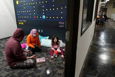 Christopher Harris, left, his wife Novi and their daughter Keeva occupy an office suite at a pop-up warming centre in Richardson, Texas. It is one of seven such places in the city, offering a place to keep warm and charge devices.  AP