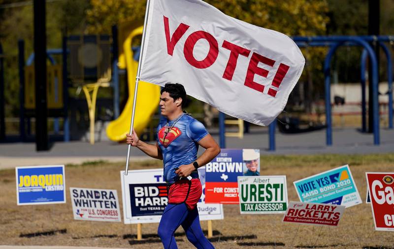 A jogger carries a Vote! flag as he passes a polling station in San Antonio.  AP