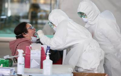 Medical workers wearing protective gear take samples from a foreign visitor at an 'Open Walking-Thru' centre for coronavirus Covid-19 tests at the airport in Incheon. EPA