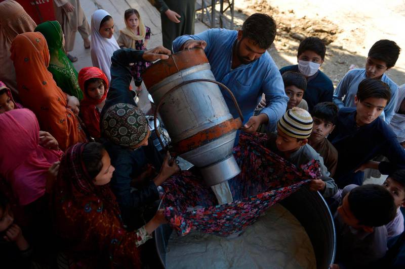A milkman pours milk into a pot before delivering to their customers in Rawalpindi.  AFP
