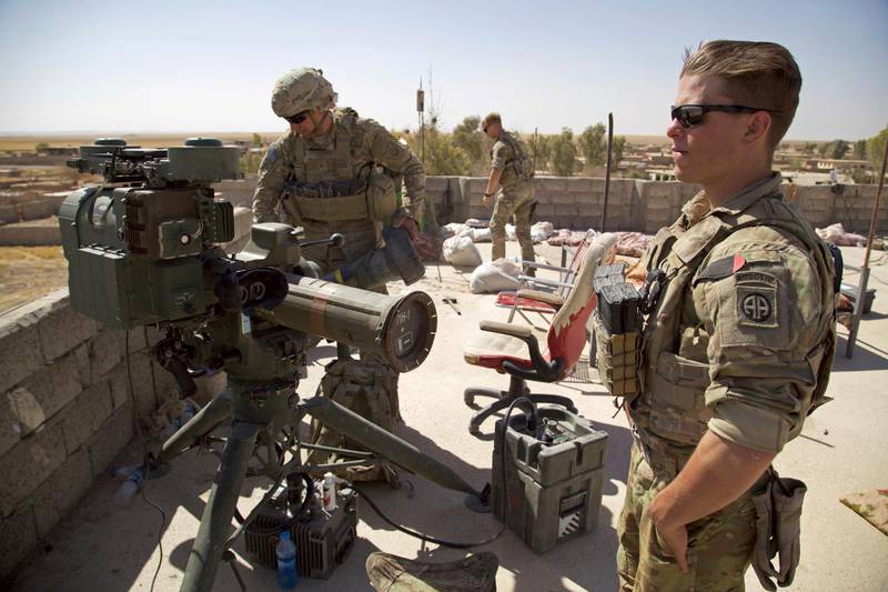 FILE - In this Aug. 20, 2017 file photo, U.S. Army soldiers stands next to a guided-missile launcher, a few miles from the frontline, in the village of Abu Ghaddur, east of Tal Afar, Iraq.  American troops have started to draw down from Iraq following Baghdadâ€™s declaration of victory over the Islamic State group last year, according to western contractors at a U.S.-led coalition base in Iraq. (AP Photo/Balint Szlanko, File)