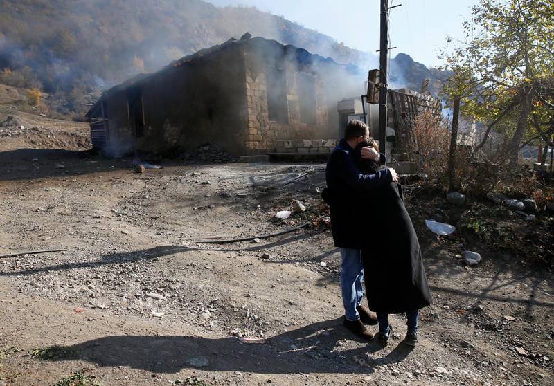 Residents hug as they stand near a house set on fire by departing Ethnic Armenians, in an area which is soon to be turned over to Azerbaijan,.  Reuters