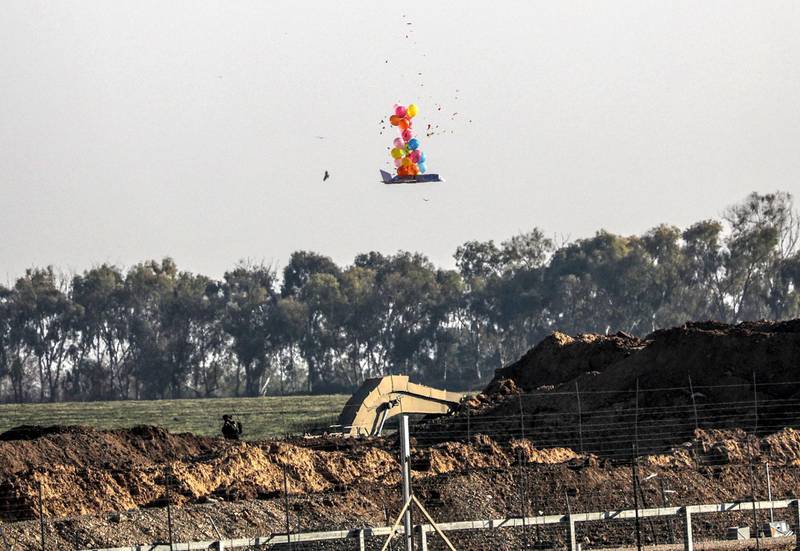 epa07456916 An Israeli soldier shoots at a balloon attached to a burning effigy sent by Palestinians protesters over the border during the clashes after Friday protests near the border between Israel and Gaza Strip, eastern Gaza Strip, 22 March 2019. According to media reports, Israeli forces killed two Palestinians and wounded 55 others during the clashes eastern Gaza Strip.  EPA/MOHAMMED SABER