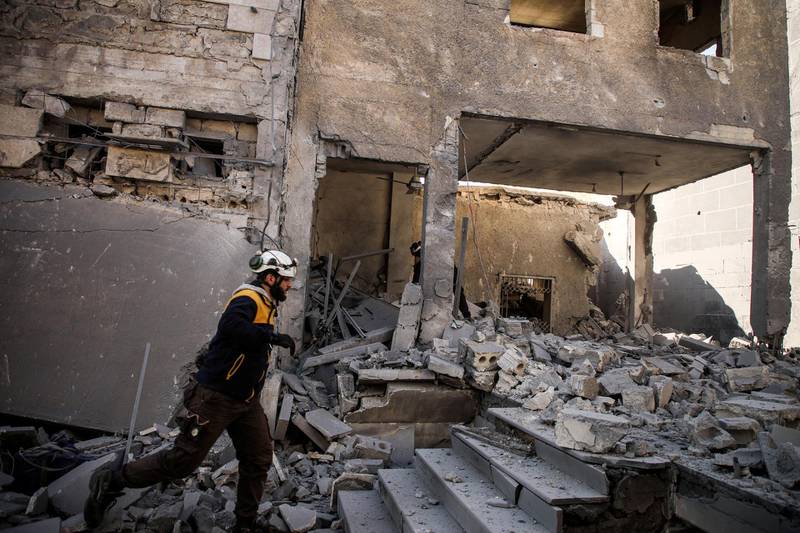 A member of the Syrian Civil Defence, also known as the "White Helmets", walks through debris and rubble while searching for survivors at a destroyed hospital in the town of Darret Ezza, about 30 kilometres northwest of the northern Syrian city of Aleppo on February 17, 2020, after a reported air strike hit the building. (Photo by AAREF WATAD / AFP)