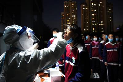 A medical worker in a protective suit collects a swab from a pupil, following new cases of coronavirus in Qingdao, Shandong province, China. Reuters