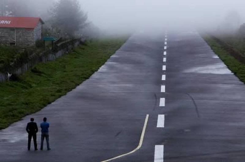 In this Sunday, May 26, 2013 photo, policemen stand on the runway during bad weather conditions at Lukla airport, Nepal. Carved out of side of a mountain, the airport was built by Sir Edmund Hillary in 1965, and at an altitude of 2,843 meters (9,325 feet) it has earned the reputation of being one of the most extreme and dangerous airports in the world. (AP Photo/Niranjan Shrestha) *** Local Caption ***  Nepal Everests Airport.JPEG-0c4be.jpg