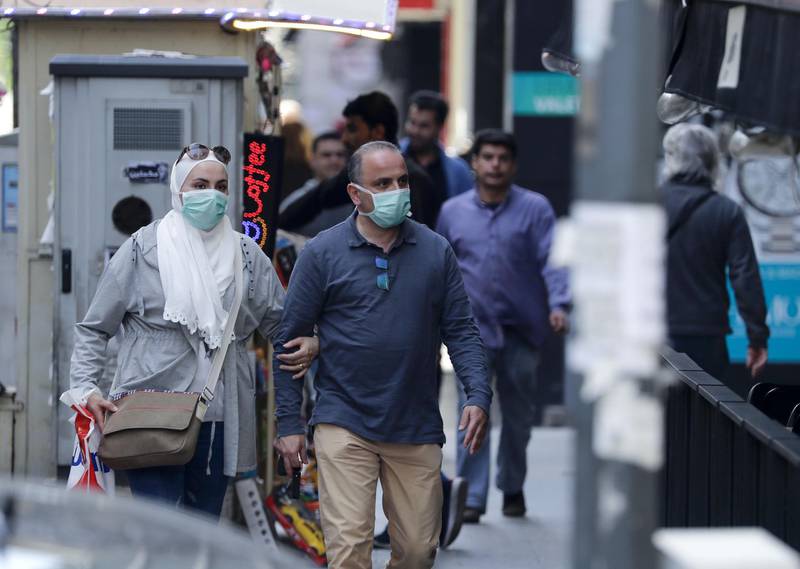 A Lebanese couple wearing protective masks walks on a shopping street in the Lebanese capital Beirut, on March 11, 2020, amid fears from the novel coronavirus outbreak. Lebanon's health ministry announced it has recorded a second death from the novel coronavirus which has been diagnosed in 61 people nationwide. / AFP / JOSEPH EID
