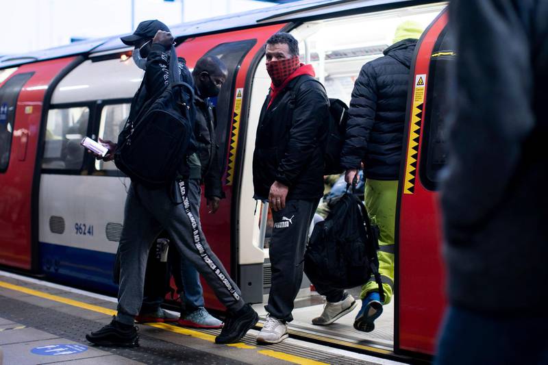 Commuters alight from a tube train wearing face masks at Canning Town station in London. AP Photo