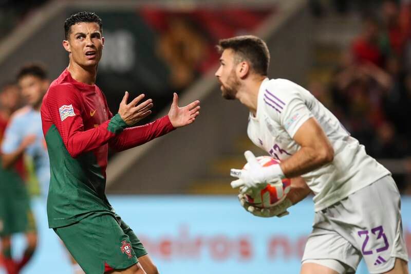 Spain goalkeeper Unai Simon collects the ball in front of a frsutrated Cristiano Ronaldo . EPA