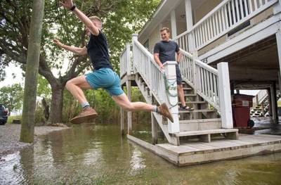 Heading out to lunch, Lucas Lindholm, 27, had to go for an Olympic-style leap from the front steps of his friend's house in Salt Bayou near Slidell. Hurricane Sally missed Louisiana, but its effect, such as high water, could be felt along the region. Kyle Wheeler, 26, right, decided just to walk through the water as they leave.   AP