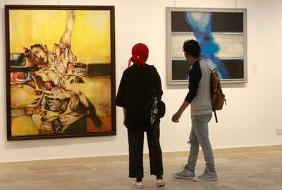 Visitors look at paintings by Iraqi artists Suad Al-Attar, left, and Rafa Al Nasiri.