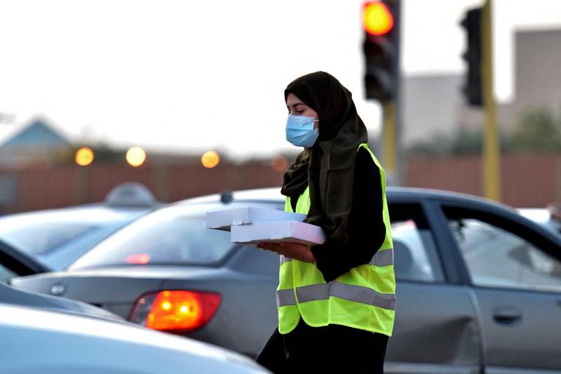 A Saudi volunteer distributes boxes of iftar meals at a traffic junction in the Saudi Arabian port city of Jeddah. AFP