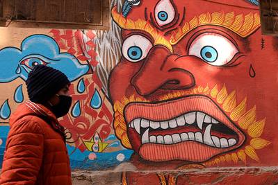 A resident wearing a protective face mask walks at the Patan Durbar Square area in Kathmandu.  AFP