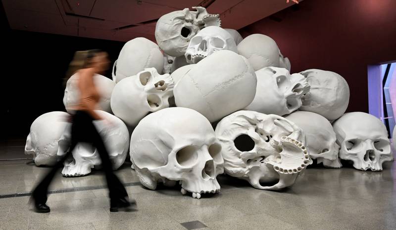 A person passes Australian artist Ron Mueck’s large-scale installation 'Mass' which comprises more than 100 hand-cast skulls at an exhibition in Melbourne. AFP