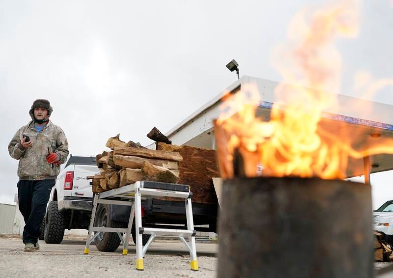 Robert Garcia burns a small container of wood to attract customers as he sells firewood in Spring, Texas. AP
