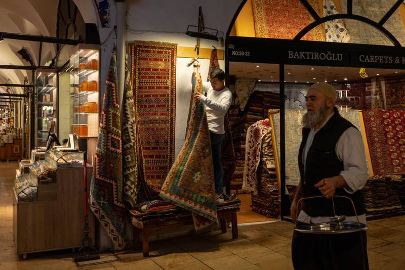 There are few shoppers in sight as a trader hangs carpets outside his store in the Grand Bazaar in Istanbul