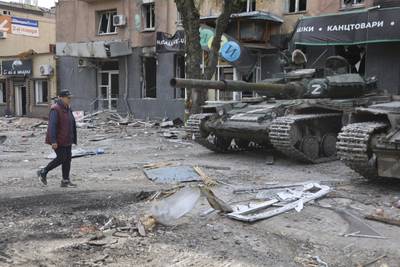 A woman passes Donetsk People's Republic militia tanks in Mariupol, eastern Ukraine. AP