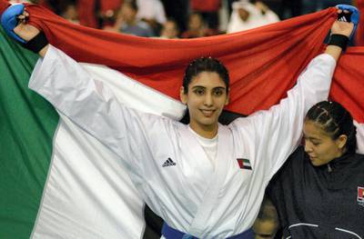 Sheikha Maitha al-Maktum, daughter of Sheikh Mohammed bin Rashid al-Maktom, Emirati Defence Minister and Dubai Crown Prince, carries her national flag after winning the single category of the Seventh GCC self-defence Cahmpionship in Manama 31 July 2003. AFP PHOTO/Adam JAN (Photo by ADAM JAN / AFP)