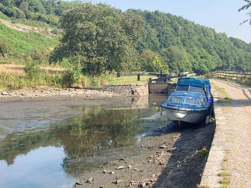 A boat lies in the dried up Huddersfield narrow canal near Linthwaite in the Colne Valley, as a drought has been declared for parts of England following the driest summer for 50 years. PA