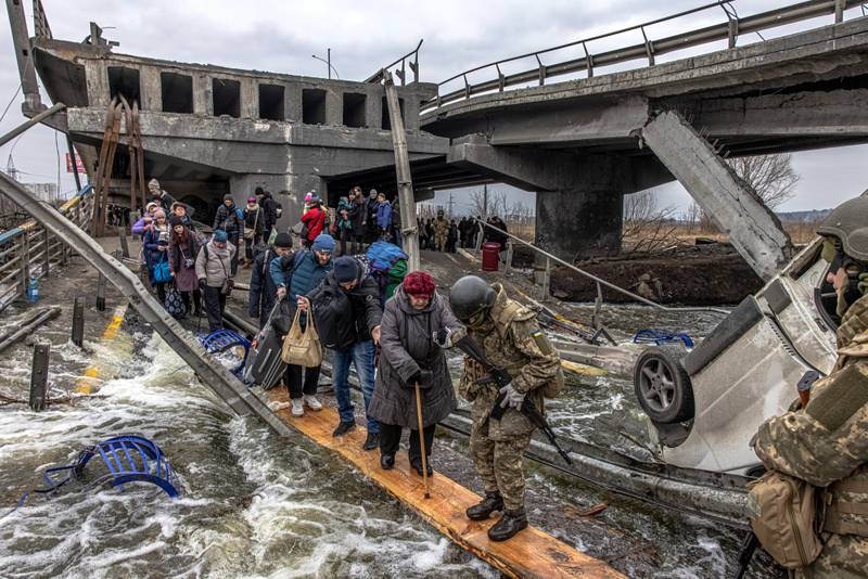 Civilians cross a damaged bridge as they flee the front-line town of Irpin, Ukraine, on March 7. EPA